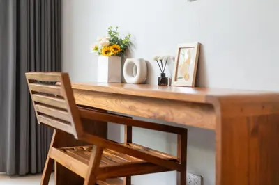 a wooden desk with a chair and flowers on it at \u5bbd\u655e\u8212\u9002 \u90a6\u6d9b\u6d77\u6ee9Laguna\u9644\u8fd1 \u56db\u5367\u5ba4\u79c1\u4eba\u6cf3\u6c60\u522b\u5885 V07 in Phuket Town