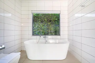 a white bathroom with a tub and a window at \u5bbd\u655e\u8212\u9002 \u90a6\u6d9b\u6d77\u6ee9Laguna\u9644\u8fd1 \u56db\u5367\u5ba4\u79c1\u4eba\u6cf3\u6c60\u522b\u5885 V07 in Phuket Town