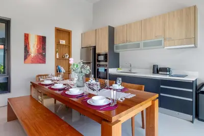 a kitchen with a wooden table with plates on it at \u5bbd\u655e\u8212\u9002 \u90a6\u6d9b\u6d77\u6ee9Laguna\u9644\u8fd1 \u56db\u5367\u5ba4\u79c1\u4eba\u6cf3\u6c60\u522b\u5885 V07 in Phuket Town