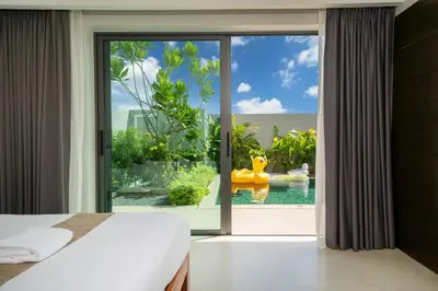 a bedroom with a view of a pool through a sliding glass door at \u5bbd\u655e\u8212\u9002 \u90a6\u6d9b\u6d77\u6ee9Laguna\u9644\u8fd1 \u56db\u5367\u5ba4\u79c1\u4eba\u6cf3\u6c60\u522b\u5885 V07 in Phuket Town