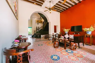 a living room with orange walls and tables and chairs at O'nya Phuket Hotel in Phuket Town