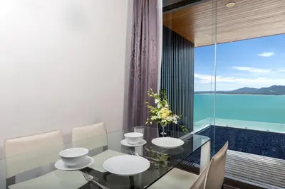 a dining room with a glass table and a view of the ocean at X10 Seaview Suites at Panwa Beach in Panwa Beach