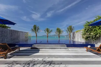 a swimming pool with palm trees and the ocean at X10 Seaview Suites at Panwa Beach in Panwa Beach
