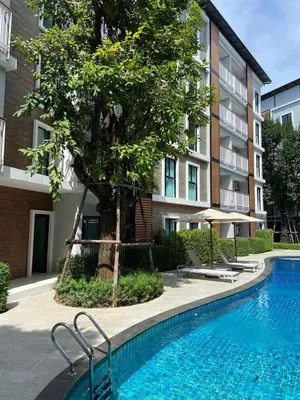 a swimming pool in front of a building with a tree at Title V Sunny Nest Sea View 5fl Pool Gym in Rawai Beach