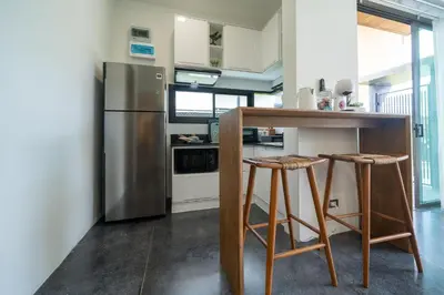 a kitchen with a stainless steel refrigerator and two bar stools at Stylish Pool Villa in Chalong-Phuket-2 Bedroom in Ban Suan