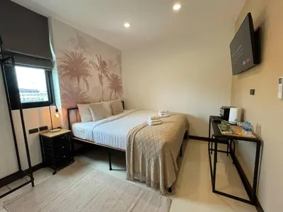 a bedroom with a bed and a tv on the wall at Mitsu Guesthouse in Karon Beach