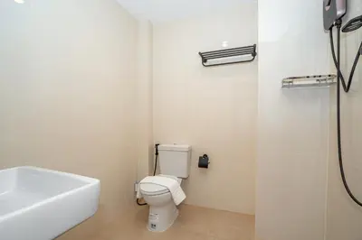 a white bathroom with a toilet and a sink at Mitsu Guesthouse in Karon Beach
