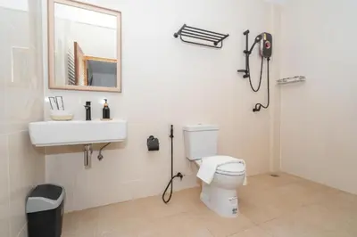a bathroom with a toilet and a sink and a mirror at Mitsu Guesthouse in Karon Beach