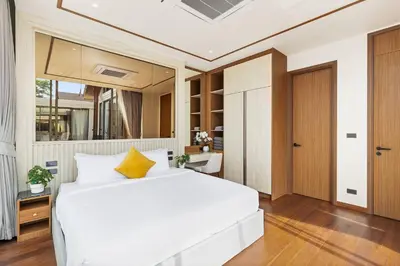 a bedroom with a large white bed with a yellow pillow at The Ozon Bangtao 3-bedrooms Villas with pool by My Home Phuket in Laguna Phuket