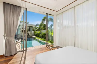 a bedroom with a bed and a view of a pool at The Ozon Bangtao 3-bedrooms Villas with pool by My Home Phuket in Laguna Phuket