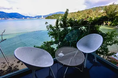 two tables and chairs on a balcony overlooking the water at Tri Trang Beachfront Apartments with Stunning Views in Patong Beach