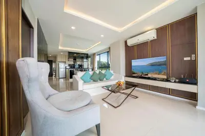 a living room with a white couch and a television at Surin sea view 3br apartment with jacuzzi in Surin Beach