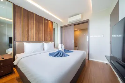 a bedroom with a large white bed and a television at Surin sea view 3br apartment with jacuzzi in Surin Beach