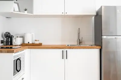 a white kitchen with white cabinets and a sink at Title Halo Vitamin Sea 40m2 King Bed Naiyang in Nai Yang Beach