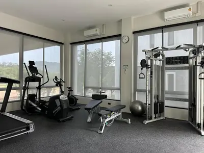 a gym with treadmills and ellipticals in a room with windows at Title Halo Vitamin Sea 40m2 King Bed Naiyang in Nai Yang Beach