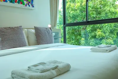 a white bed with towels on it with a window at C251 Beachfront gym Sauna 7 Swimming Pool in Rawai Beach