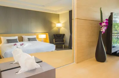 a hotel room with a bed and a vase of flowers at The Capuchin Hotel Krabi, Ao Nang Beach in Ao Nang Beach
