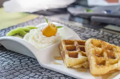 a white plate with waffles and waffle syrup and a waffleaffleasy at The Capuchin Hotel Krabi, Ao Nang Beach in Ao Nang Beach