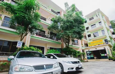 two cars parked in a parking lot in front of a building at RK Guesthouse in Patong Beach
