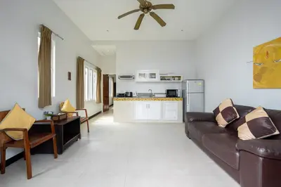 a living room with a brown couch and a kitchen at Hillside Seaview Residence in Karon Beach
