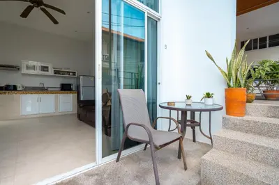 a room with a table and a chair and a kitchen at Hillside Seaview Residence in Karon Beach