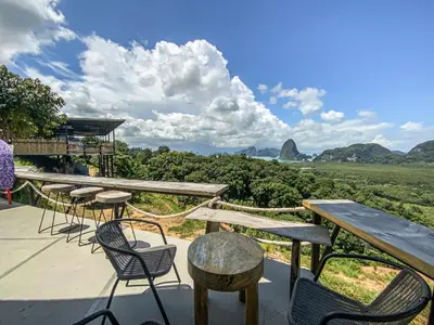 a patio with tables and chairs and a view of mountains at Samet Nangshe Goodview in Ban Met Nang Chi
