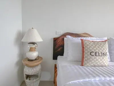 a bedroom with a bed with a lamp on a table at Samet Nangshe Goodview in Ban Met Nang Chi