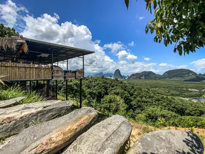 a building on a hill with large rocks at Samet Nangshe Goodview in Ban Met Nang Chi