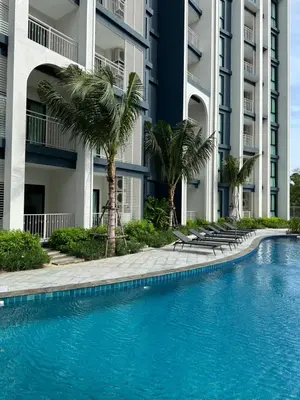 a swimming pool in front of a building with palm trees at Title Halo Timeless Naiyang Pool Gym Sauna in Nai Yang Beach