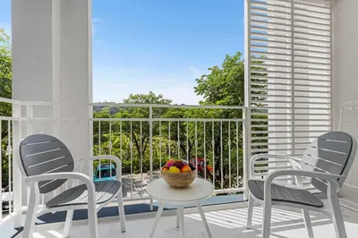 a balcony with chairs and a bowl of fruit on a table at The Title Halo NaiYang by My Home Phuket in Nai Yang Beach