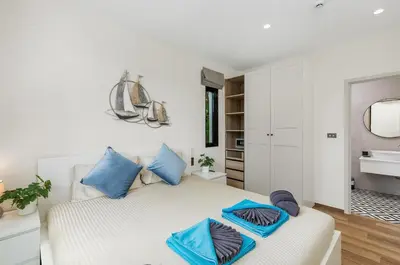 a white bedroom with blue pillows on a bed at The Title Halo NaiYang by My Home Phuket in Nai Yang Beach