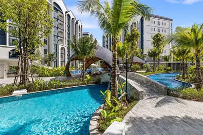 a swimming pool with palm trees and buildings at The Title Halo NaiYang by My Home Phuket in Nai Yang Beach