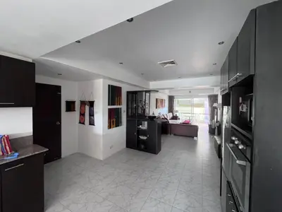 a kitchen with black cabinets and a living room at Rawai apartments in Ban Saiyuan (1)