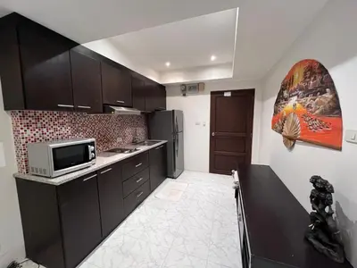 a kitchen with black cabinets and a microwave at Rawai apartments in Ban Saiyuan (1)
