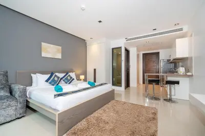 a bedroom with a bed and a couch and a kitchen at Studio Apartment - Emerald Terrace Patong in Patong Beach
