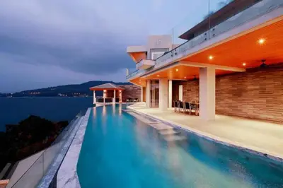 a swimming pool on the side of a house at Cape Sienna Villa 4-Oceanfront 5-Bedroom Luxury Villa with 22 m Infinity Pool in Kamala Beach