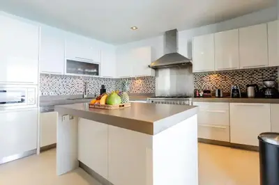 a kitchen with white cabinets and a bowl of fruit on a counter at Cape Sienna Villa 4-Oceanfront 5-Bedroom Luxury Villa with 22 m Infinity Pool in Kamala Beach