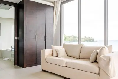 a white couch in a living room with large windows at Cape Sienna Villa 4-Oceanfront 5-Bedroom Luxury Villa with 22 m Infinity Pool in Kamala Beach