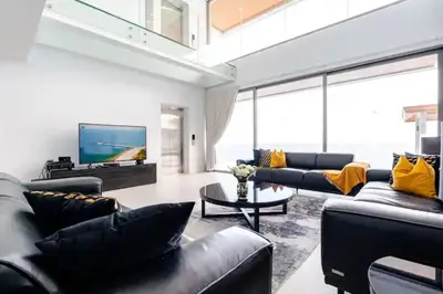a living room with black leather furniture and a flat screen tv at Cape Sienna Villa 4-Oceanfront 5-Bedroom Luxury Villa with 22 m Infinity Pool in Kamala Beach