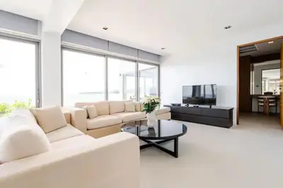 a living room with a white couch and a tv at Cape Sienna Villa 4-Oceanfront 5-Bedroom Luxury Villa with 22 m Infinity Pool in Kamala Beach