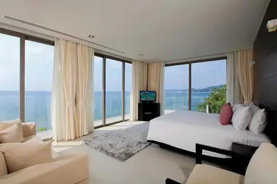 a bedroom with a large bed and large windows at Cape Sienna Villa 4-Oceanfront 5-Bedroom Luxury Villa with 22 m Infinity Pool in Kamala Beach