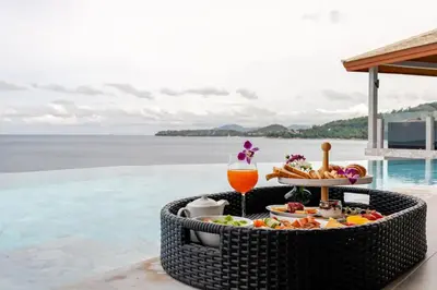 a tray of food and a drink on a table by a pool at Cape Sienna Villa 4-Oceanfront 5-Bedroom Luxury Villa with 22 m Infinity Pool in Kamala Beach