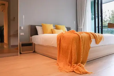 an orange blanket laying on a bed in a room at Cassia Residences Sea View in Laguna Phuket