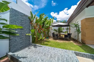 a garden with a table and chairs and an umbrella at Luxury 4 Bedrooms 800 square meters of large space Private swimming pool private kitchen service Family and friends vacation in Bang Tao Beach