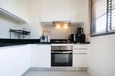 a kitchen with white cabinets and a black oven at Laguna pool house in Phuket Town