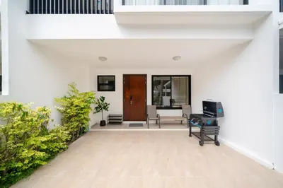 an open living room with white walls and a wooden door at Laguna pool house in Phuket Town