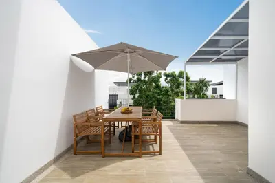 a table and chairs with an umbrella on a balcony at Laguna pool house in Phuket Town