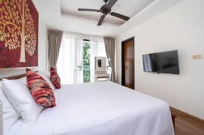 a white bed with pillows and a flat screen tv at Laguna pool house in Phuket Town