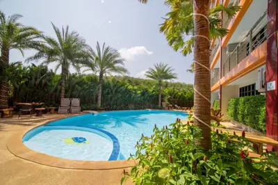 a swimming pool in front of a house with palm trees at NOVA Condo 1BR Pool View NBC Nai Harn in Rawai Beach