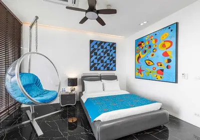 a bedroom with a bed and a blue chair at Villa Yin, Private Oceanfront Villa, Kamala Beach in Kamala Beach